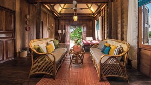 Una habitación acogedora con muebles de mimbre, un ventilador de techo y vistas al exterior.