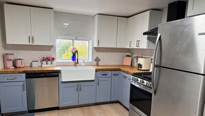Una cocina moderna con armarios grises, un refrigerador de acero inoxidable, un horno empotrado y una ventana con vistas al verdor.