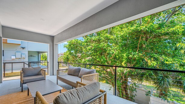 Ein Balkon mit Korbmöbeln, einem Tisch und Blick auf üppiges Grün.