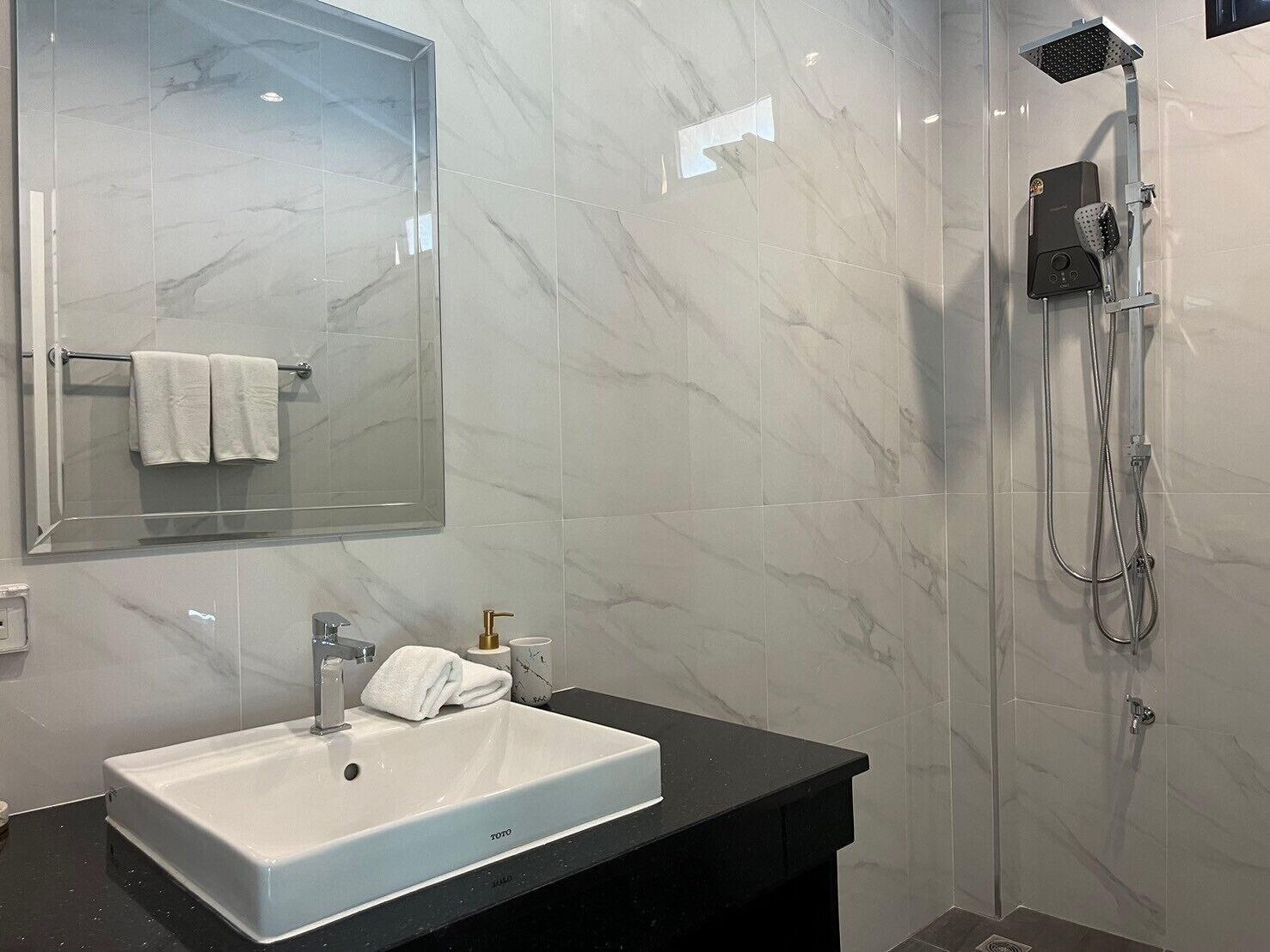Une salle de bain moderne avec un lavabo blanc, un miroir et un espace douche.