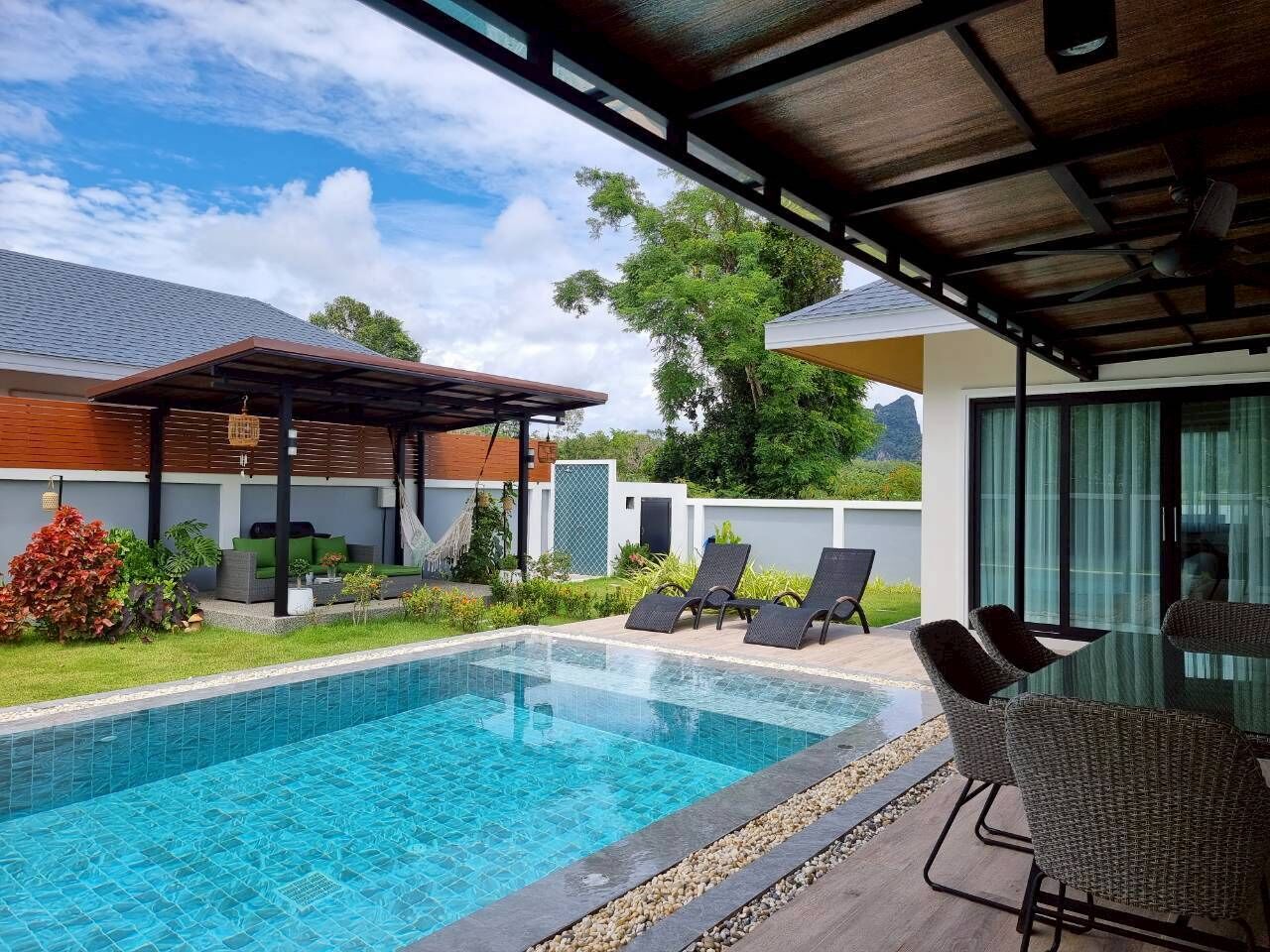A swimming pool with lounge chairs and a covered patio area.