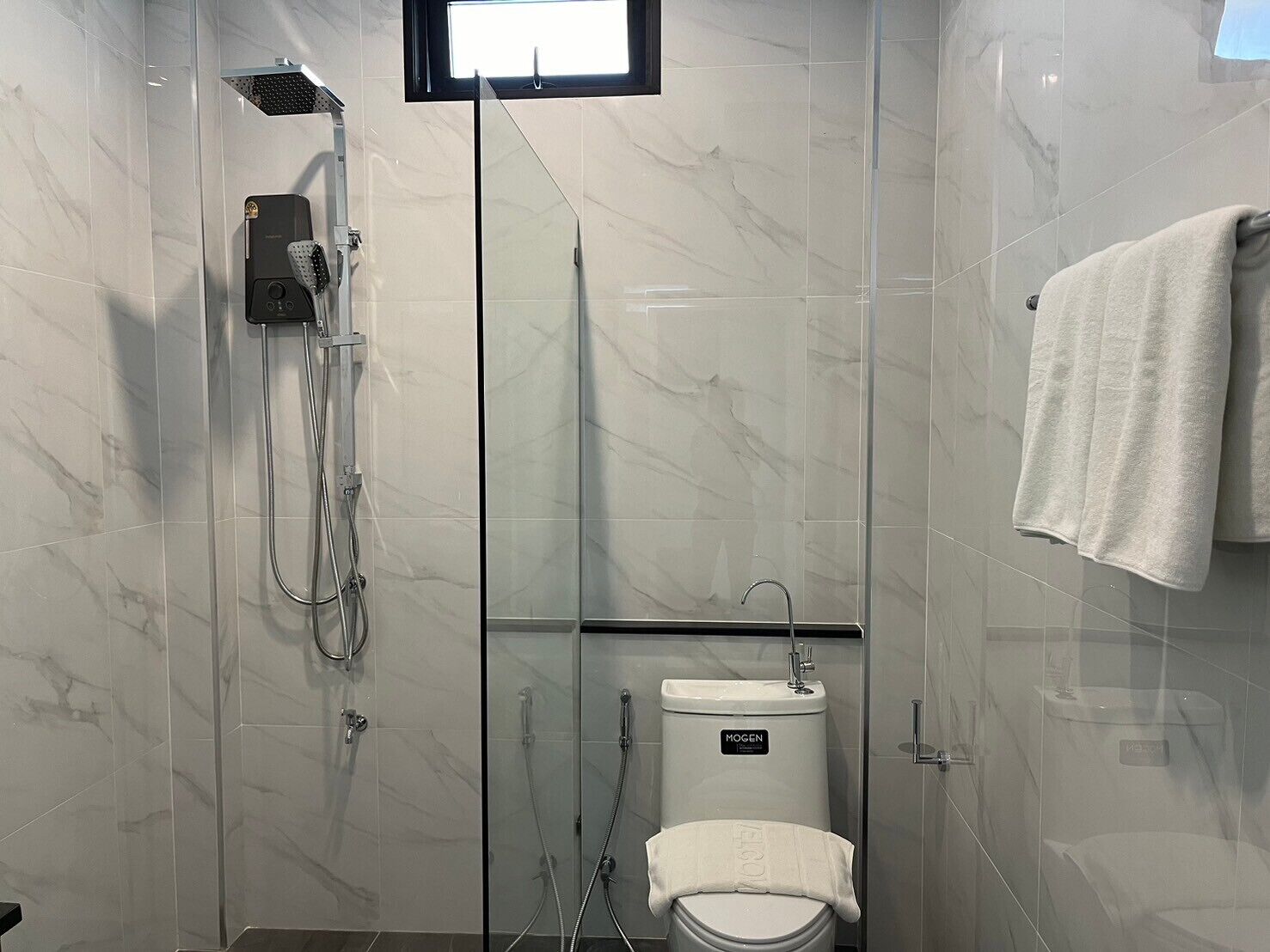Un baño moderno con ducha acristalada, inodoro y lavamanos.
