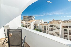A balcony with a chair and a view of buildings with terracotta roofs.