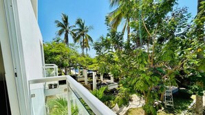 Un balcon donnant sur un jardin luxuriant et des palmiers.