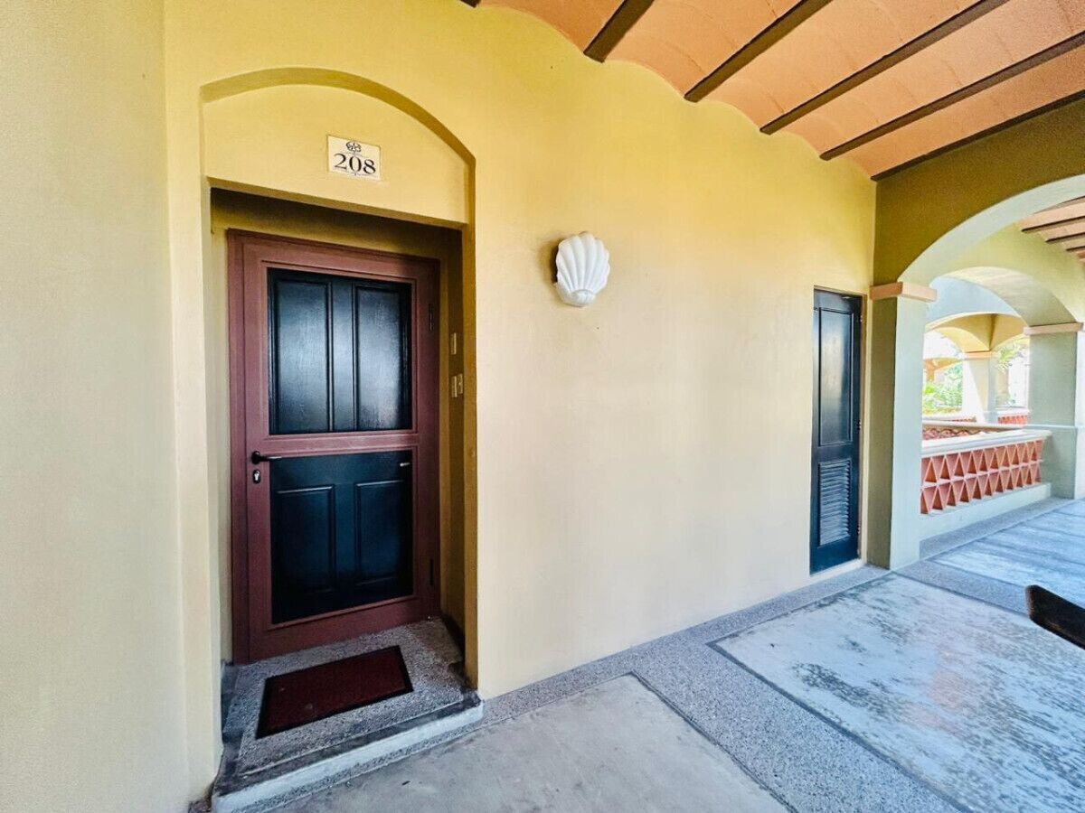 A building entrance with a numbered door, a small porch area, and a tiled floor.