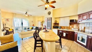 A spacious living area with a central island, a kitchen with dark cabinetry, and a dining area with chairs. - hermoso depa frente al mar by PartnerHost (Mazatlán)