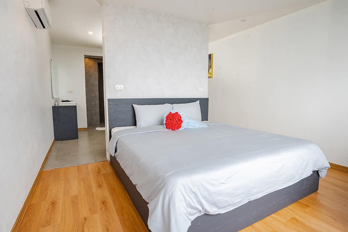 Una habitación de hotel moderna con una cama grande, una mesita de noche y un escritorio pequeño.