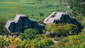 A rural landscape with green fields and a few traditional houses with sloped roofs. - Dragonfly Hotel Nghia Lo - Free Sauna & Onsen (Nghia Lo)