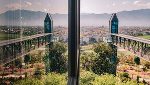 A view from a window overlooking a bridge with two towers, a cityscape, and mountains in the distance. - Dragonfly Hotel Nghia Lo - Free Sauna & Onsen (Nghia Lo)