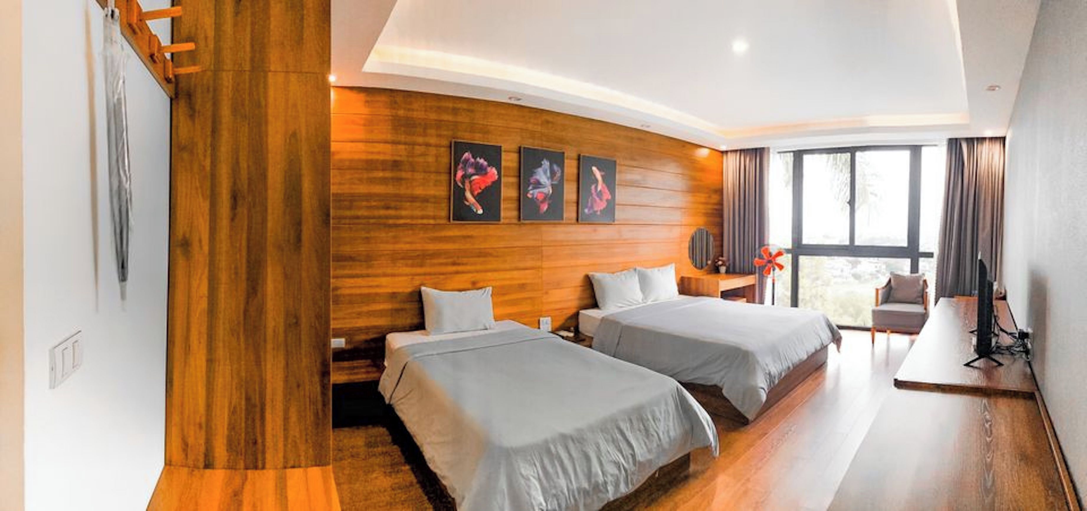 Una habitación de hotel moderna con dos camas, paneles de madera, una obra de arte en la pared y un ventanal grande.