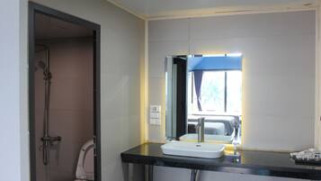 A bathroom with a shower, toilet, sink, and a mirror with a window above it.