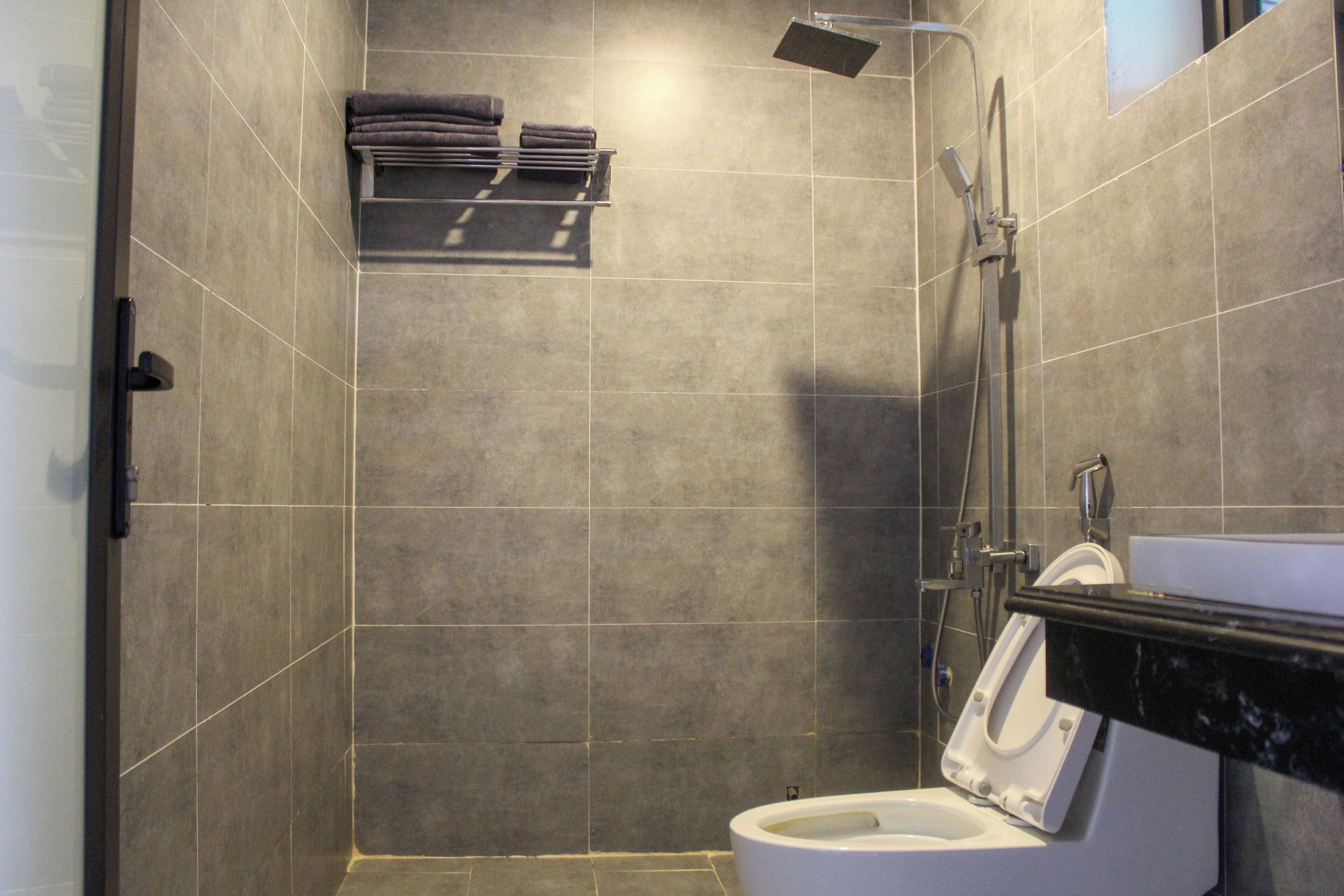 A modern bathroom with a shower, toilet, and a towel rack.