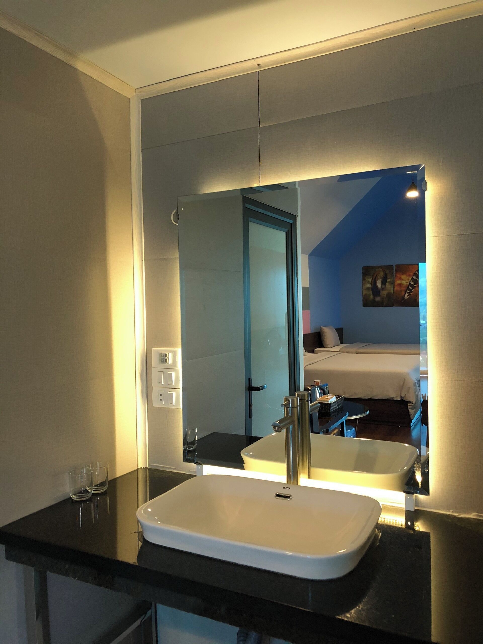 A modern bathroom with a large mirror, a white sink, and a black countertop.