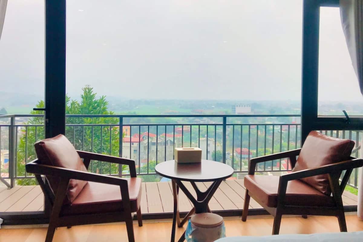 Un balcón con dos sillas y una mesita, con vistas a un paisaje urbano.