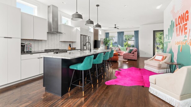 Een moderne keuken met een centraal eiland, barkrukken en hanglampen.