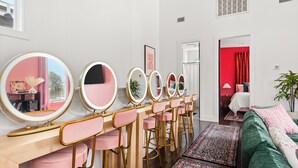 Een kamer met een kaptafel met spiegels, een groene bank en een rood gordijn op de achtergrond.