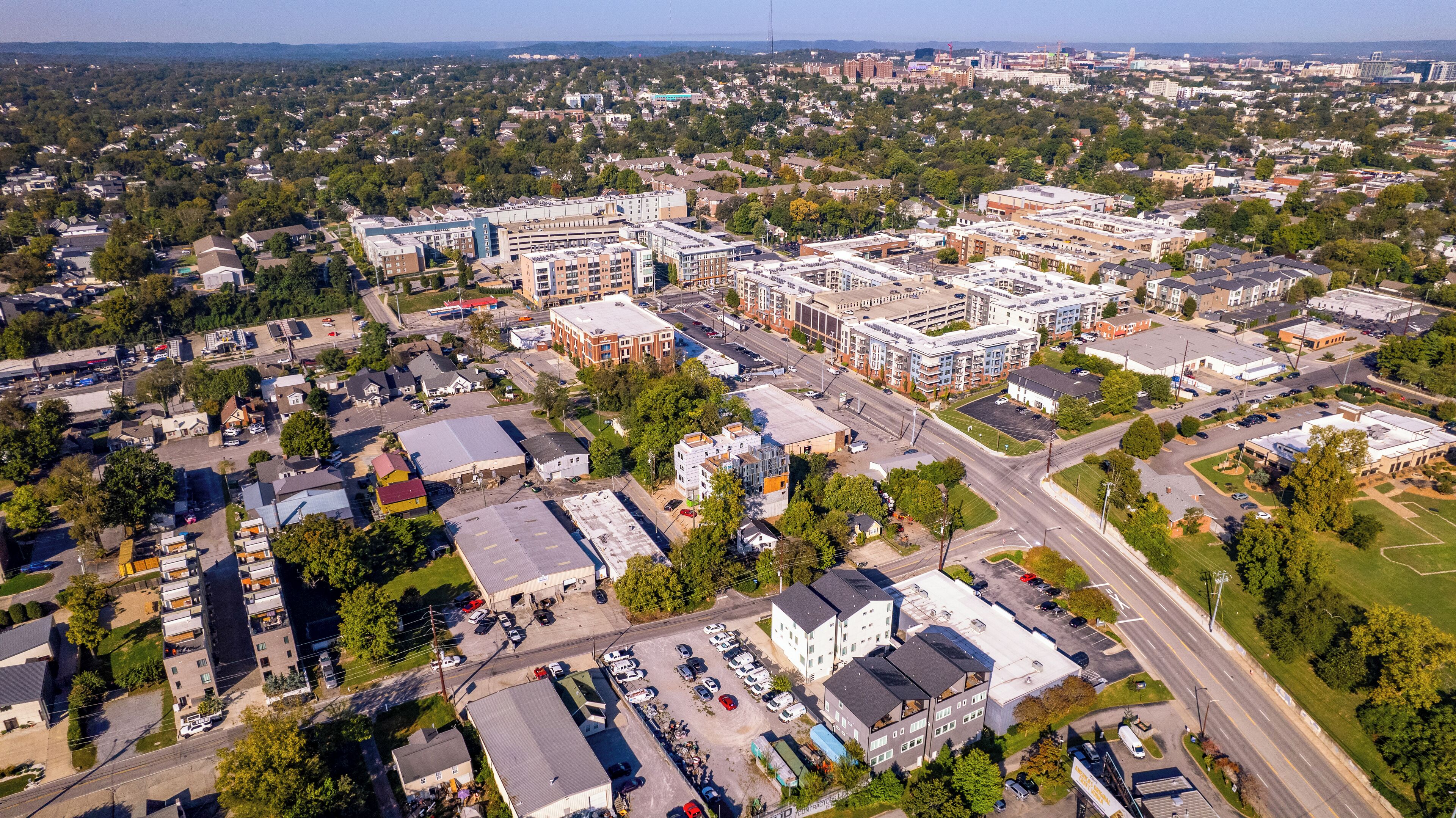 An aerial view of a cityscape with various buildings, roads, and green spaces.