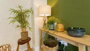 A room with a bamboo plant on a stool, a lamp on a shelf, and a woven basket.