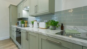 A kitchen with light green cabinets, a white countertop, a microwave, a toaster, and a potted plant.
