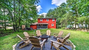 Une maison rouge avec un foyer et des chaises en bois disposées en cercle.