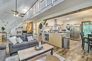 A modern open-plan living and dining area with a kitchen, a staircase, and a view of the outdoors.