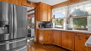 Eine Küche mit Holzausstattung, Edelstahlgeräten und einem Fenster mit Vorhängen.