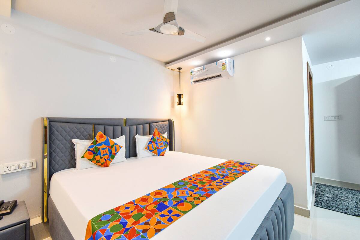 Hotelkamer met een bed, nachtkastje, plafondventilator, airconditioning en een deur naar een andere kamer.