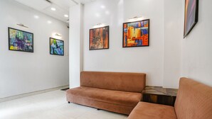Eine moderne Lobby mit einem braunen Sofa, weißen Wänden und drei abstrakten Gemälden.
