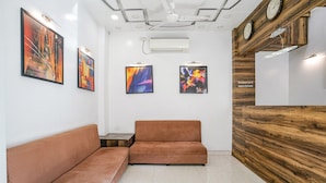 Ein Empfangsbereich mit einem Holzbüro, einem braunen Sofa und abstrakten Kunstwerken an den Wänden.