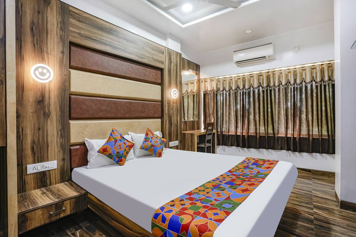 Una habitación de hotel moderna con una cama grande, cabecero de madera y un panel decorativo en la pared.