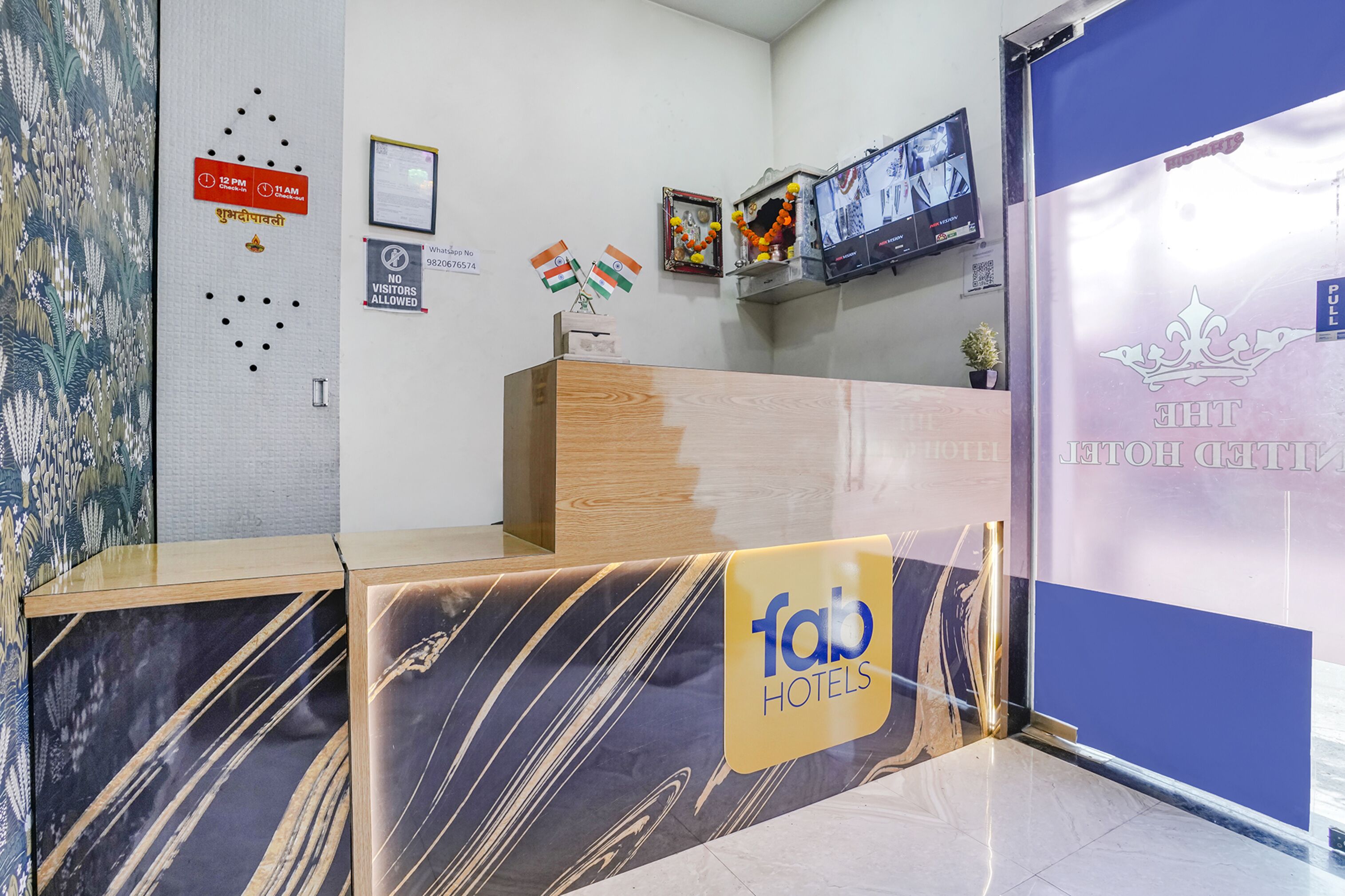 A hotel reception desk with a marble design, a clock, and a sign indicating visitor hours.