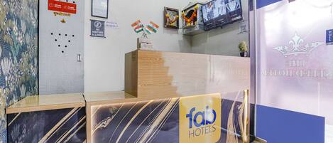 A hotel reception desk with a marble design, a clock, and a sign indicating visitor hours.