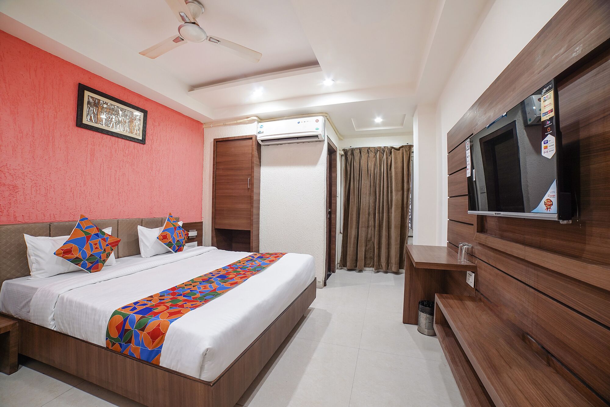 A hotel room with a bed, a TV, a wardrobe, and a ceiling fan.