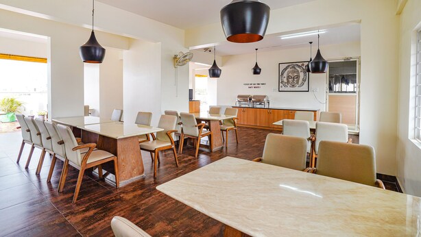 A modern meeting room with a long table, multiple chairs, and pendant lighting. - Fabhotel Northern Suites (Bengaluru)