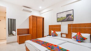 A hotel room with a large bed, wooden wardrobe, bedside tables, and a painting on the wall. - Fabhotel Northern Suites (Bengaluru)