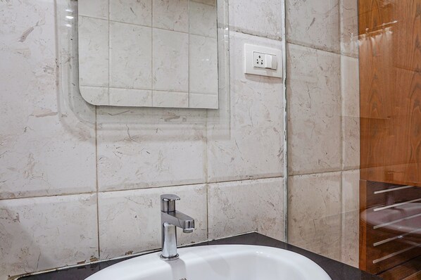 Un baño con un lavabo blanco, un espejo y un panel de madera a la derecha.