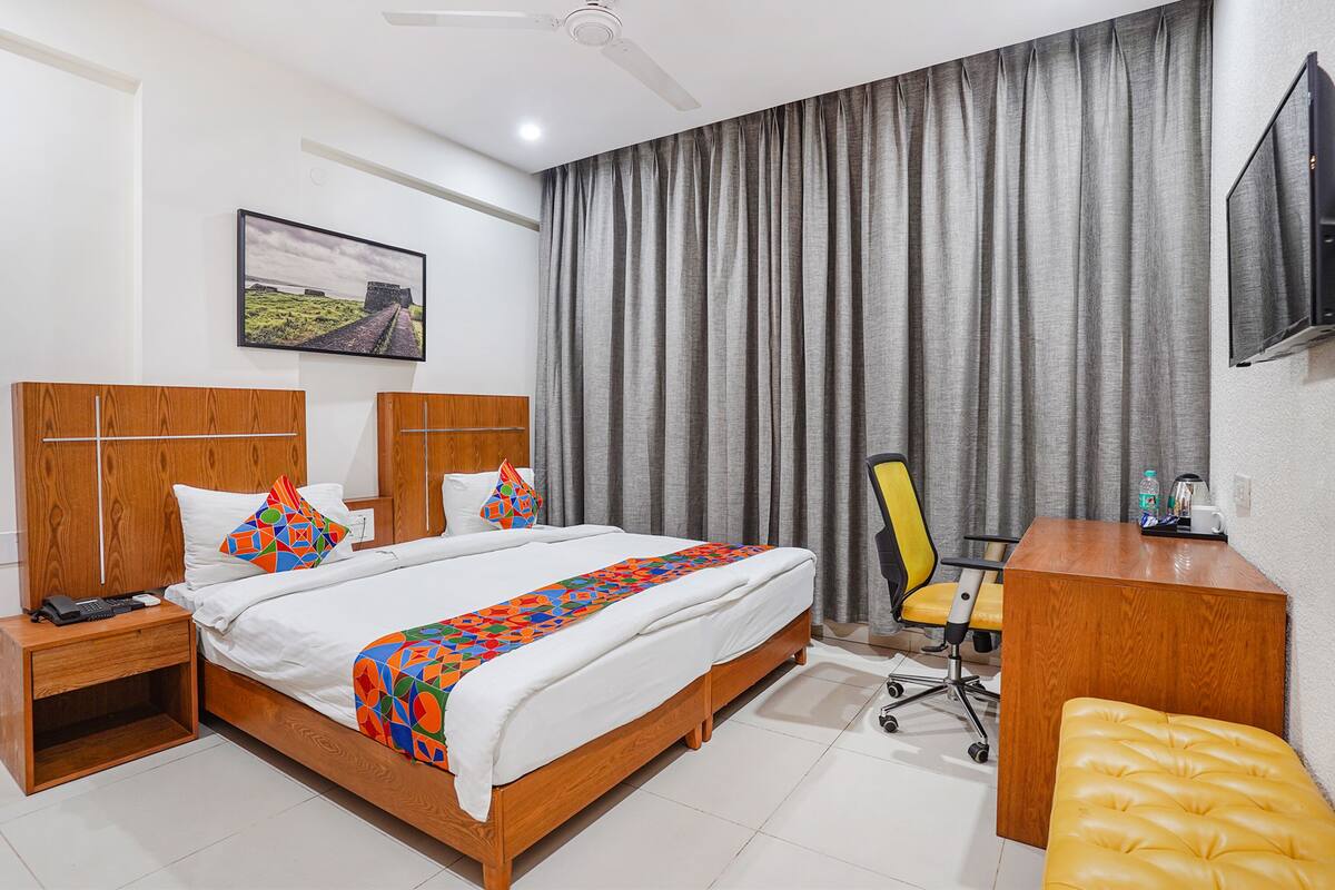 A hotel room with a wooden bed, a desk, a chair, and a television on the wall.