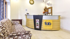 A reception area with a curved desk, a sofa, and a clock on the wall. - Fabhotel Basera (Haridwar)