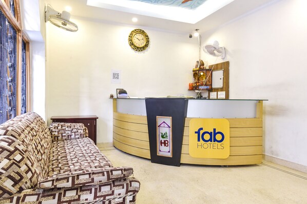 A reception area with a curved desk, a sofa, and a clock on the wall. - Fabhotel Basera (Haridwar)