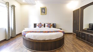 A circular bed with a wooden frame, a white bedspread, and two decorative pillows. There is a large mirror on the right side of the room. - Fabhotel Basera (Haridwar)