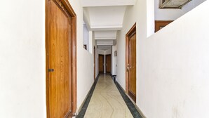 A narrow hallway with wooden doors and a marble floor. - Fabhotel Basera (Haridwar)