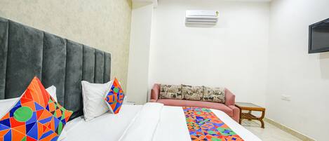 Ein Hotelzimmer mit Bett, einer Sitzecke, einem kleinen Tisch und einem an der Wand montierten Fernseher.
