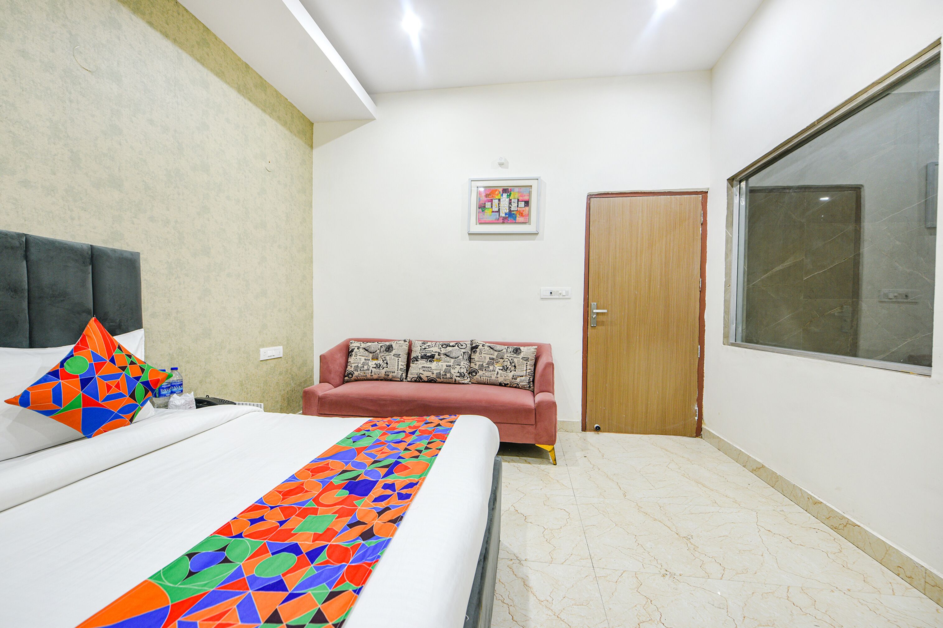 Una habitación de hotel con cama, sofá, una ventana grande y una puerta.