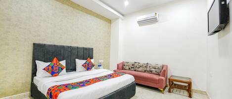 A bedroom with a bed, a sofa, a TV, and an air conditioning unit.