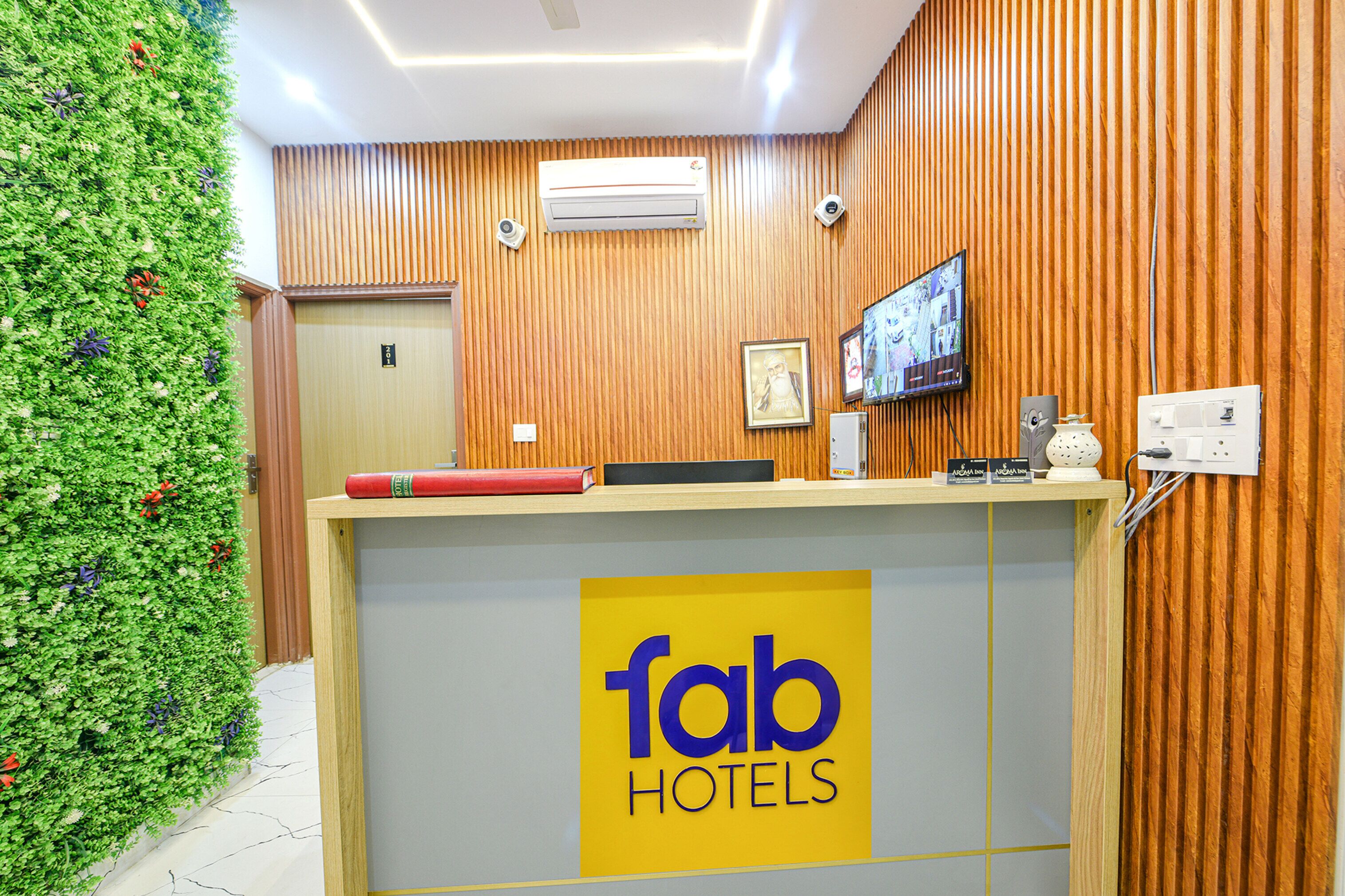 A reception desk with a 'fab hotels' sign, a television, and a wooden wall.