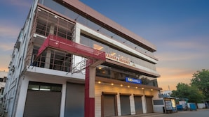 Un edificio de varios pisos con un letrero que indica "Krishna Regency" y "Fab Hotels" en la planta baja.