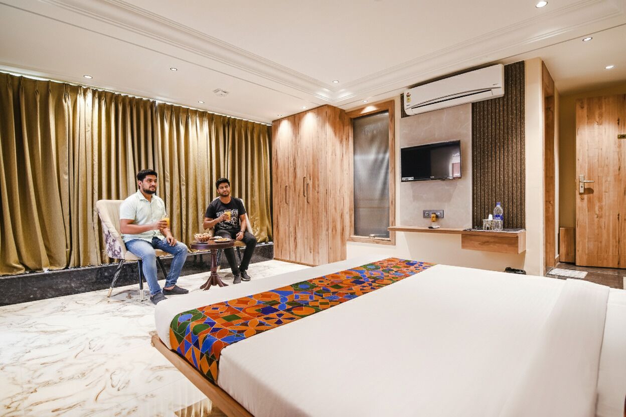 Una habitación de hotel con una cama grande, un armario de madera, un televisor y un escritorio con una silla.