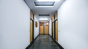 A long, narrow hallway with doors on both sides, a tiled floor, and recessed lighting on the ceiling. - Fabhotel Sunrise Villa (New Delhi)