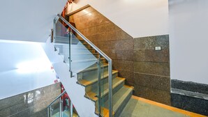 A staircase with glass railings and a mix of brown and black tiles. - Fabhotel Sunrise Villa (New Delhi)