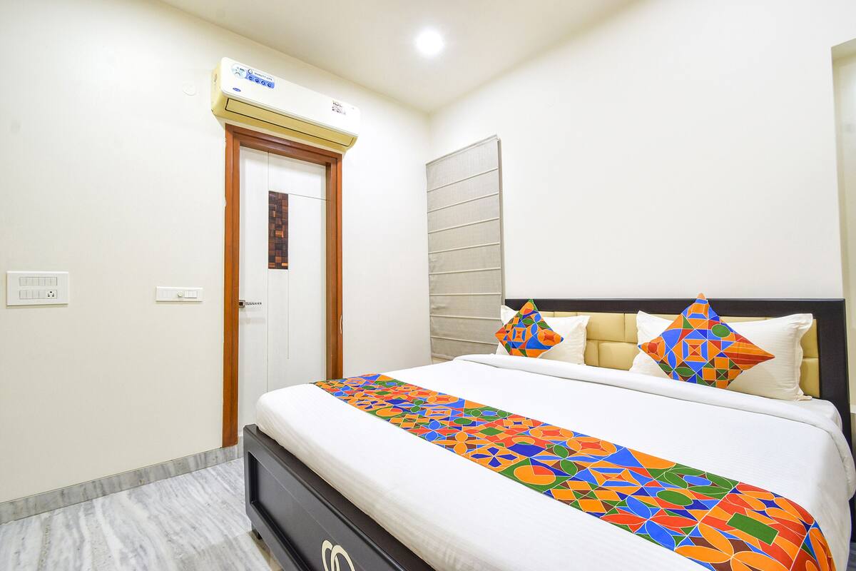 Une chambre d’hôtel avec un lit, une porte, un appareil de climatisation et un interrupteur sur le mur.